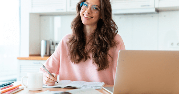 Pessoa estudando em um computador, com livros ao redor